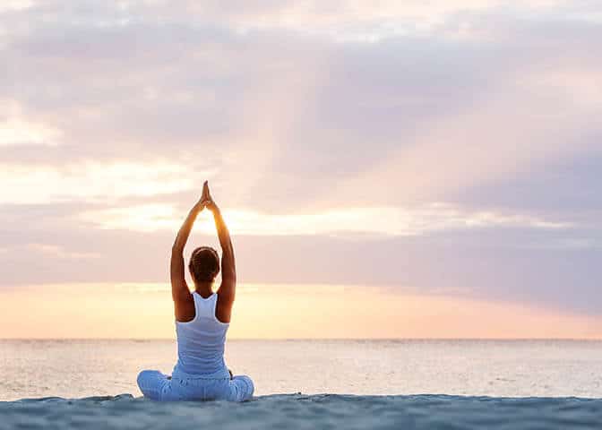 Woman Stretching and Meditating in Front of the Ocean